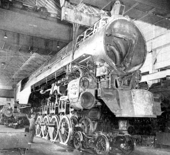 steam locomotive shop crane holding boiler assembly over running gear